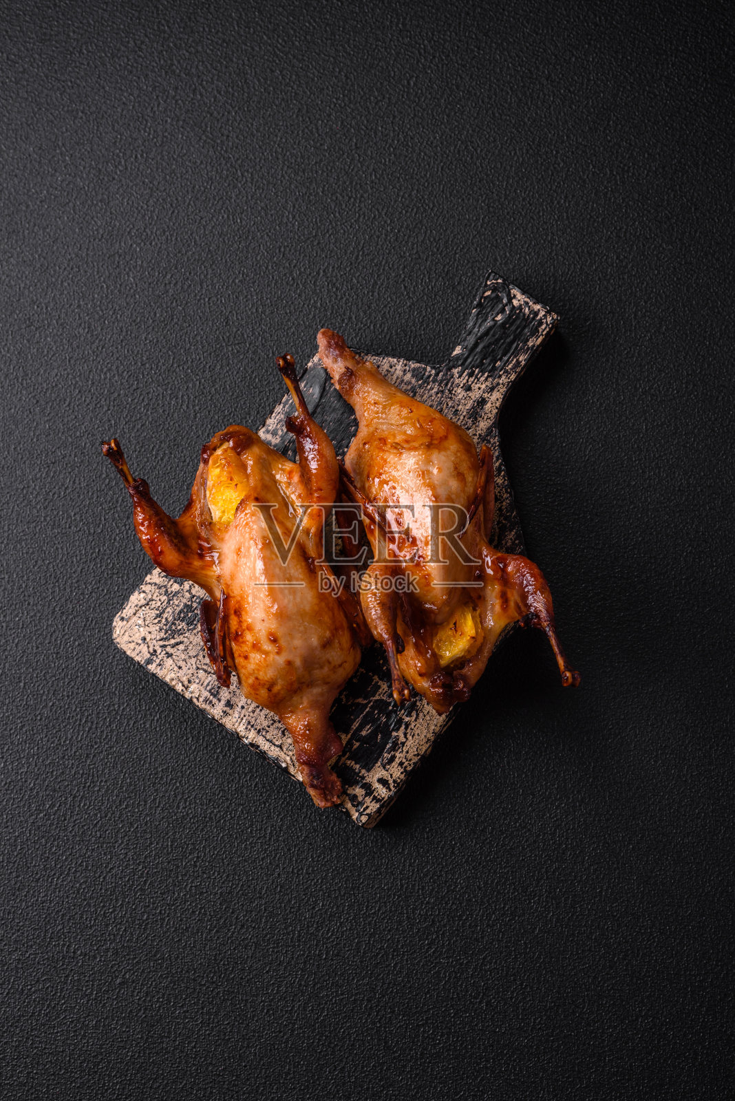 烤鹌鹑、鹧鸪或鸽子，用香料和香草填充橘子照片摄影图片