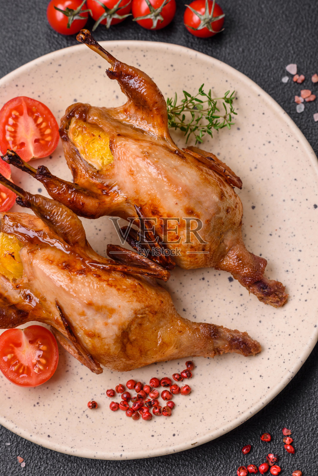 烤鹌鹑、鹧鸪或鸽子，用香料和香草填充橘子照片摄影图片