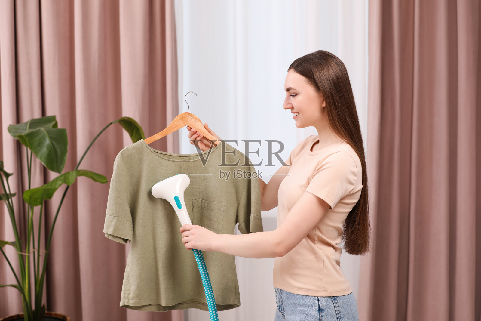 女人在家里的衣架上蒸衬衫照片摄影图片