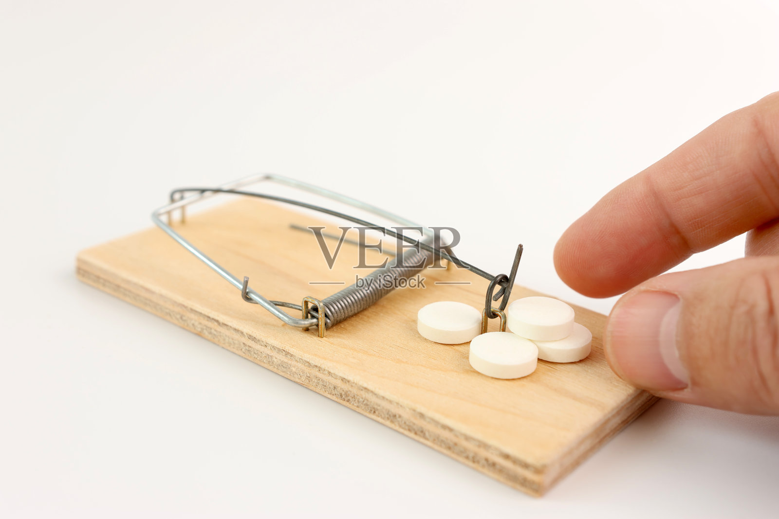 一个人在老鼠夹里放了一个药丸作为诱饵。药物成瘾的概念。照片摄影图片