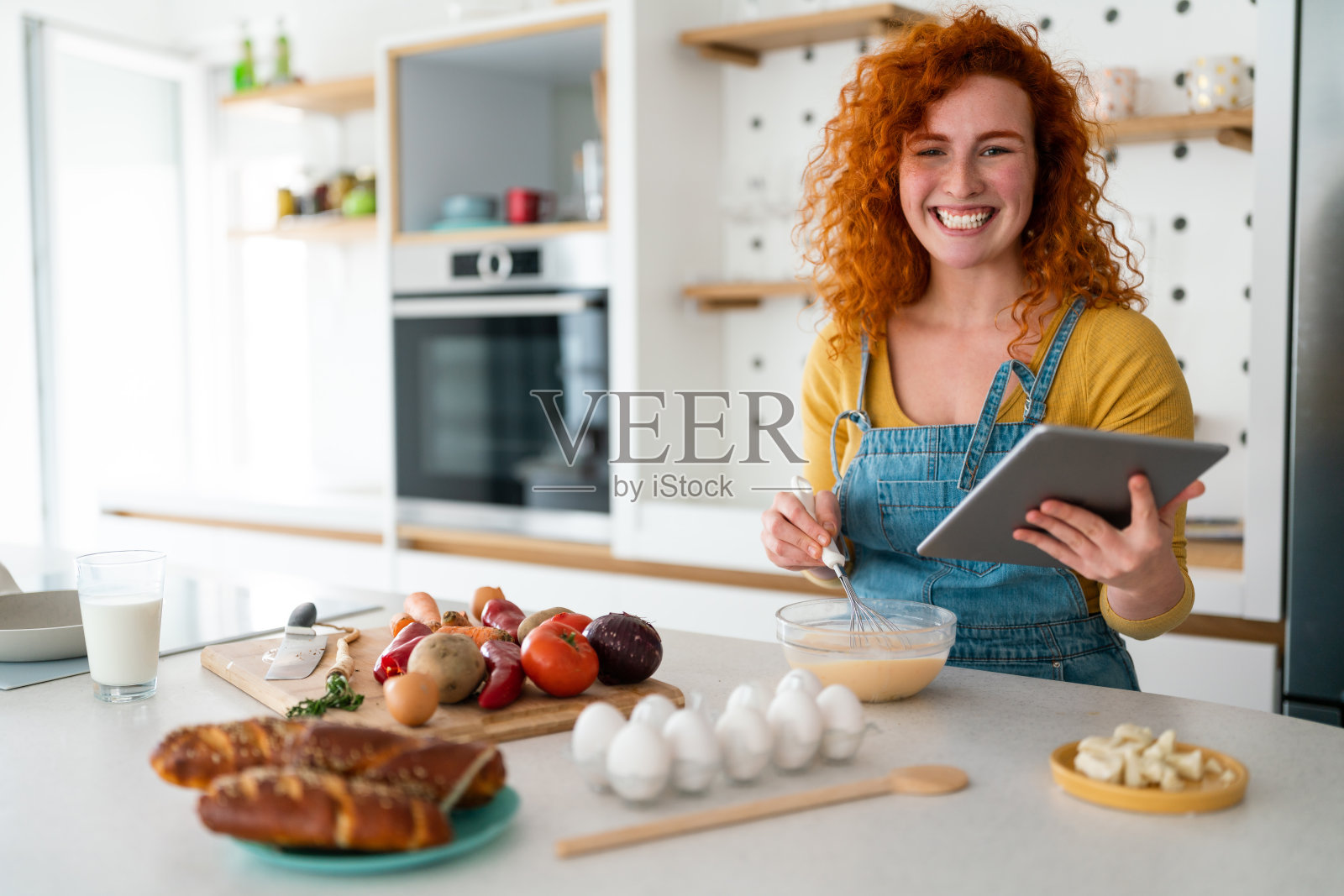 年轻女子一边看着相机，一边在平板电脑上搜索菜谱照片摄影图片