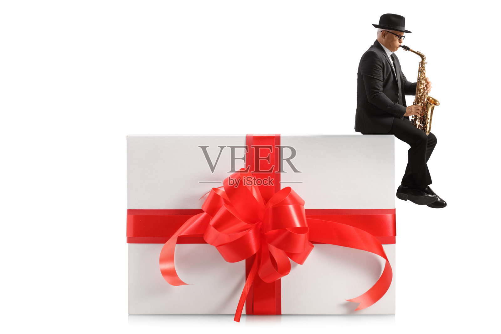 一个成熟男人吹萨克斯，坐在礼物上的全长侧面照照片摄影图片