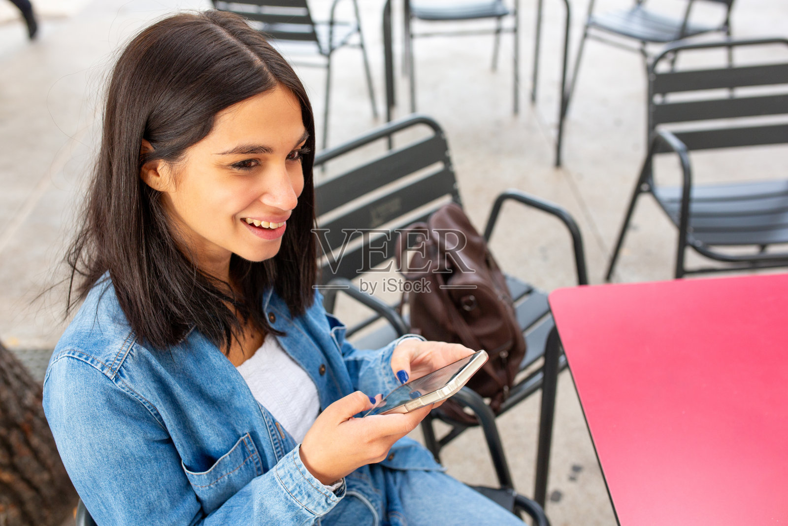近距离拍摄一个用手机微笑的女人照片摄影图片