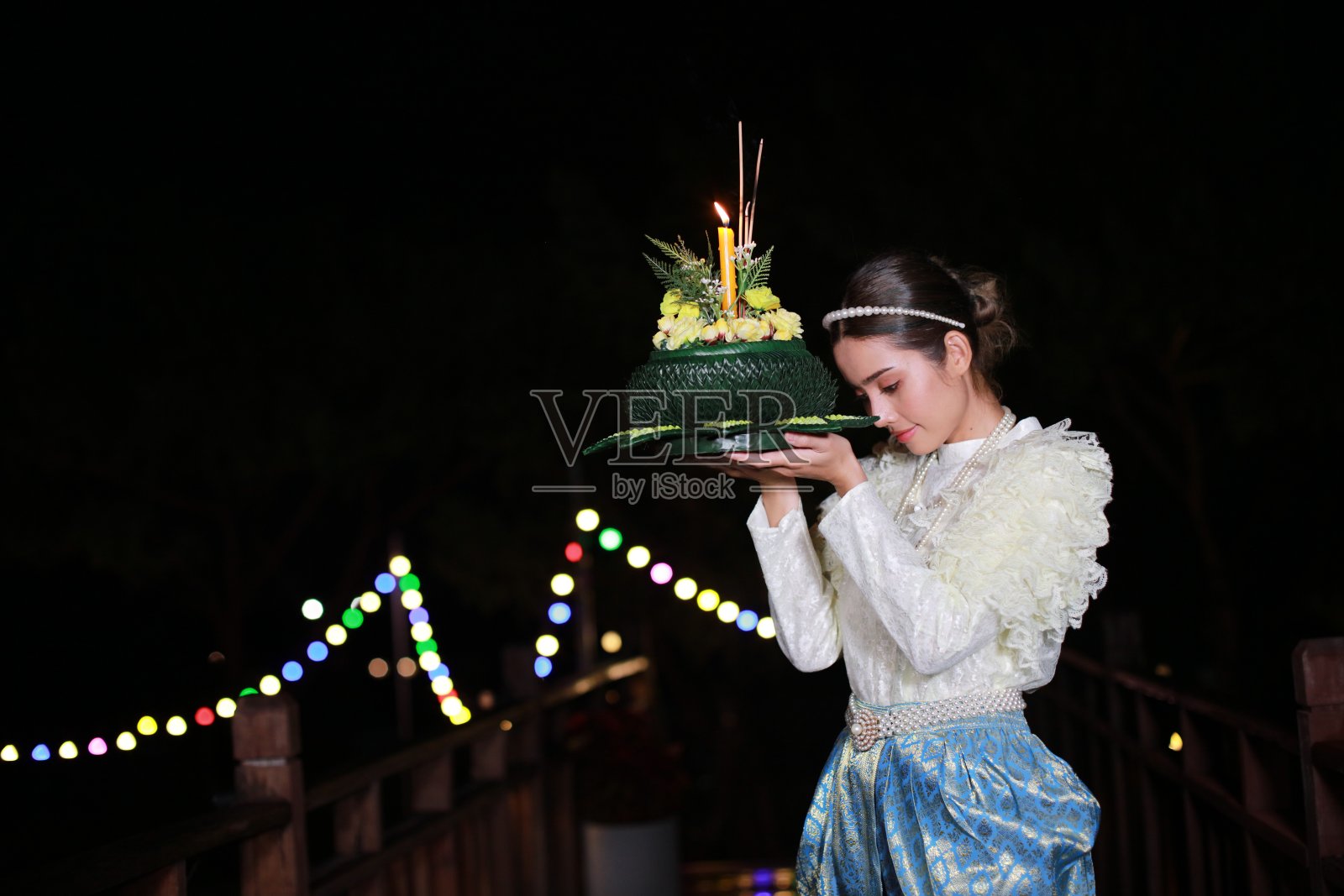 在泰国泼水节当天，一名迷人的女子穿着一件古老的泰国服装，背景是模糊的散景灯照片摄影图片