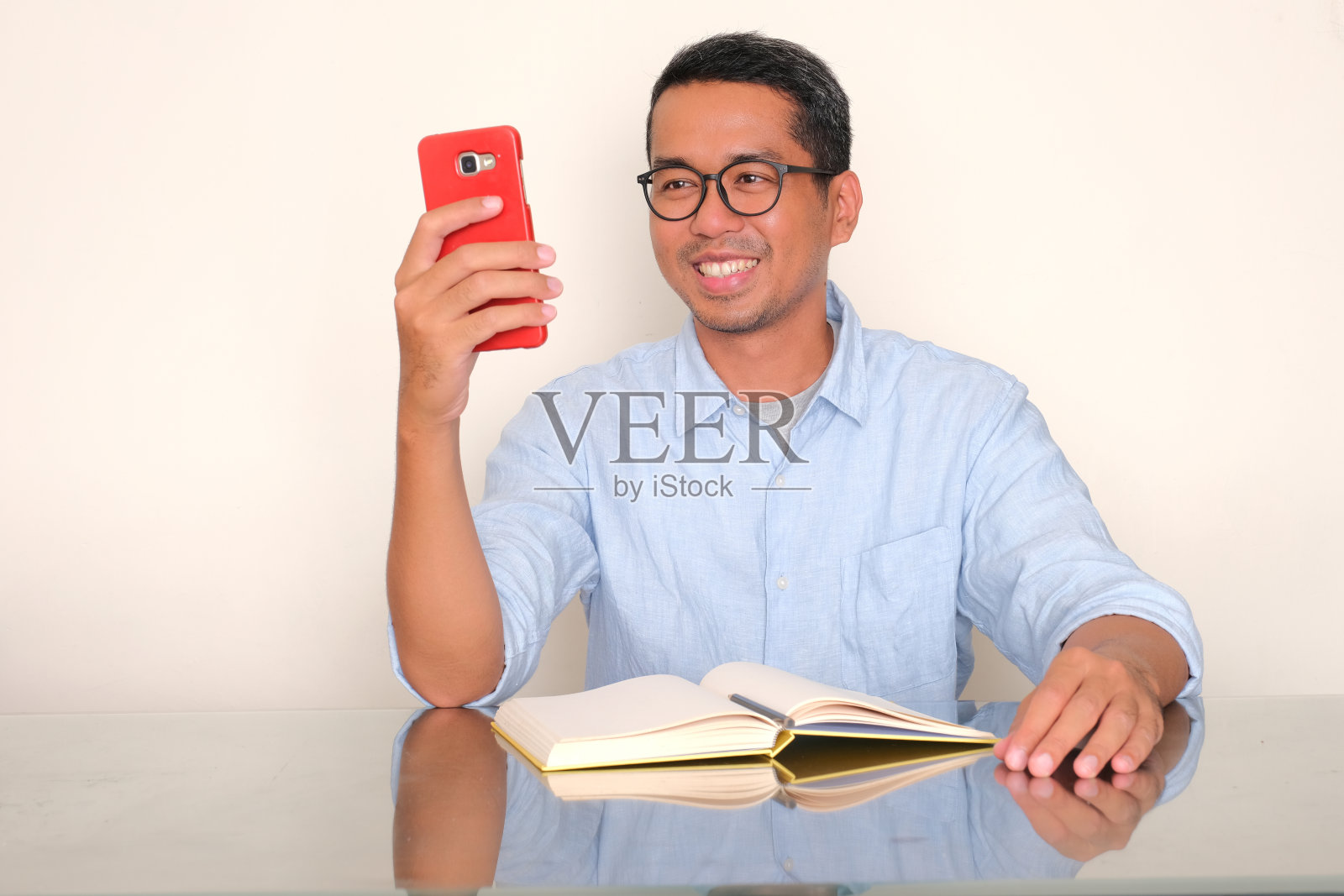 一个男人坐在那里，看着他的手机，脸上露出快乐的表情照片摄影图片