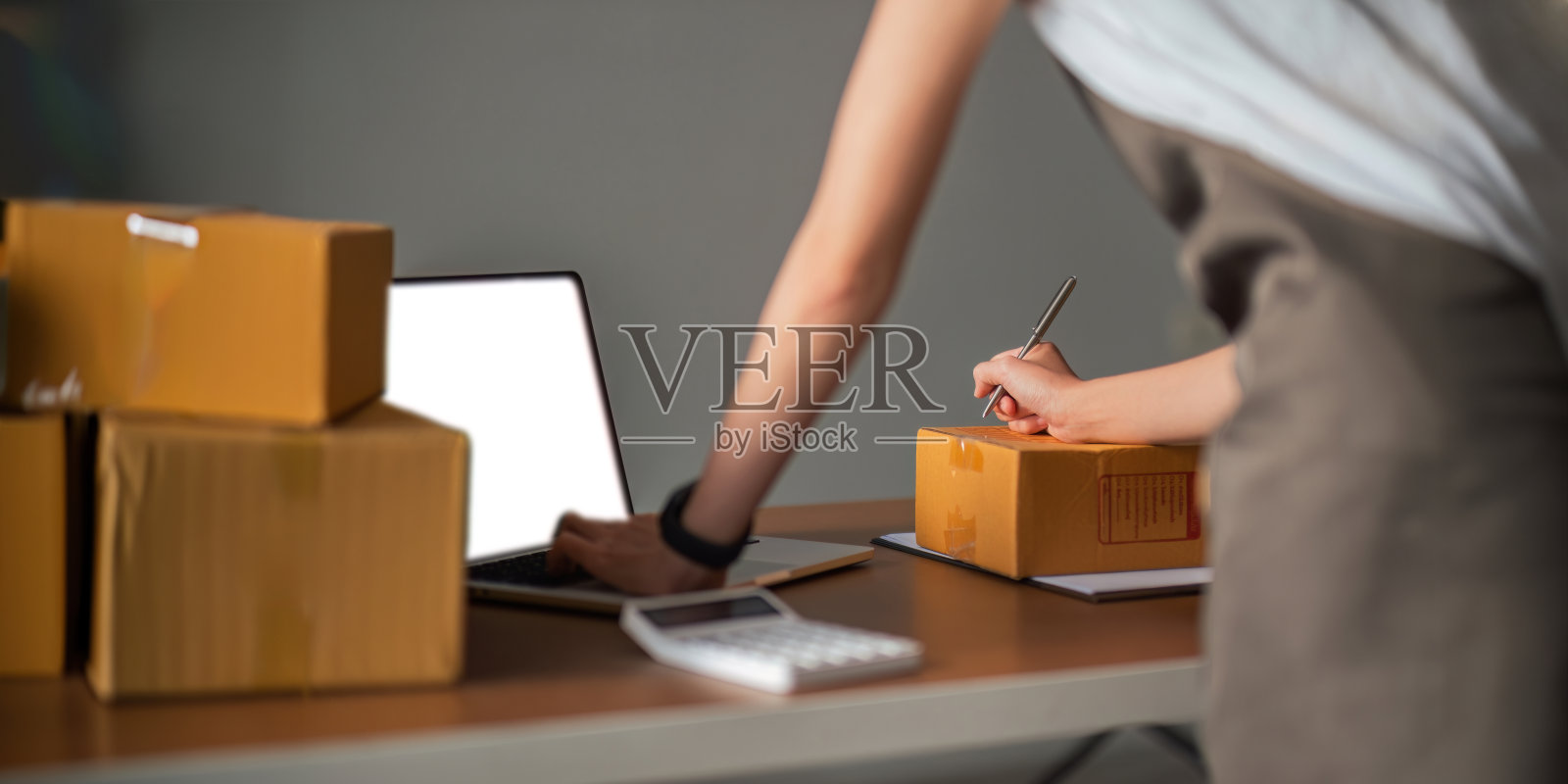 一位亚洲女性在发货前在纸上写一份客户名单，她在网站和社交媒体上经营着一家电子商务企业照片摄影图片