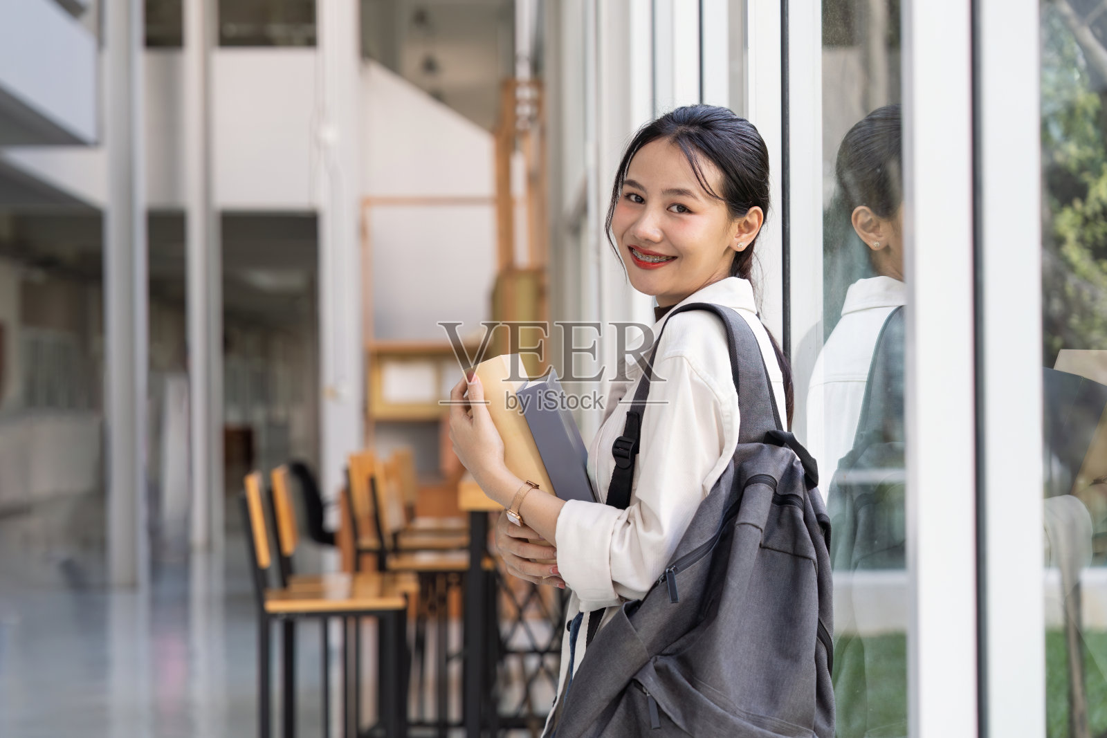 漂亮的年轻亚洲女人背着背包和书。大学生带着很多书在大学校园照片摄影图片