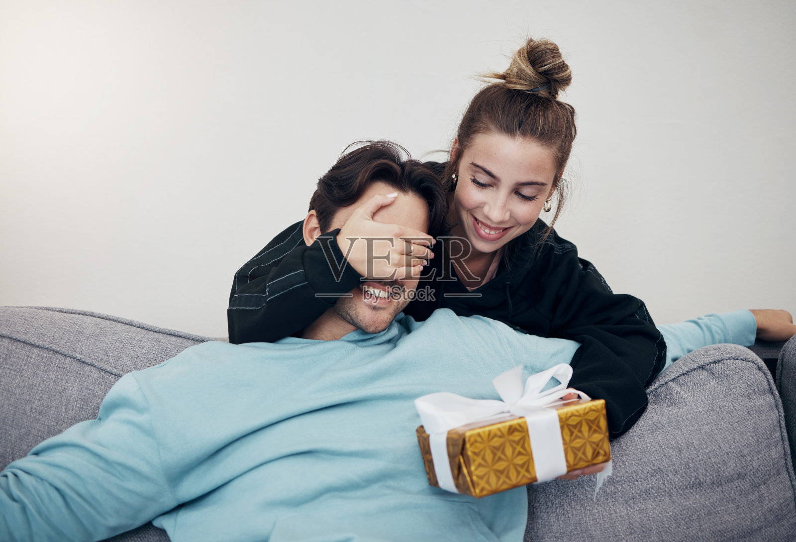 惊喜，礼物和夫妇在沙发上的生日，庆祝或周年纪念日在家里。礼物，盒子和人们在客厅里用猜游戏的礼物，浪漫或祝贺手势在一个房子里照片摄影图片