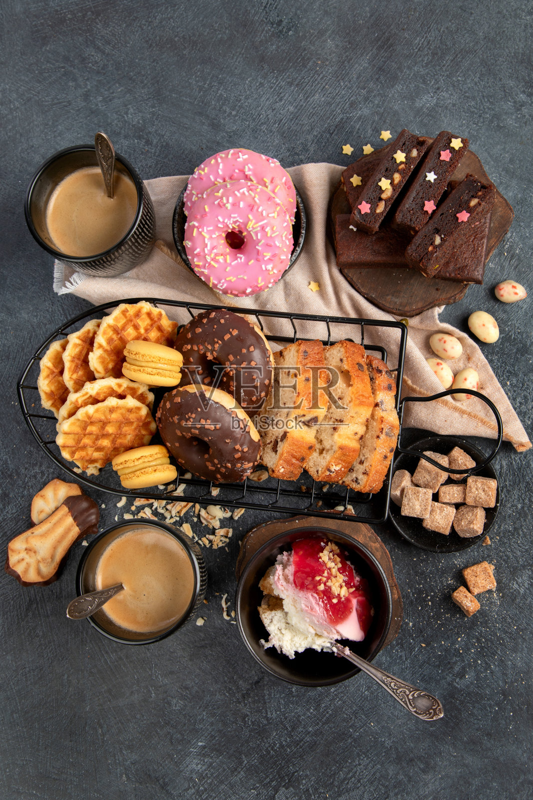 白咖啡配美味的饼干、甜甜圈、蛋糕、糖、华夫饼。深色背景的热饮加糖。照片摄影图片