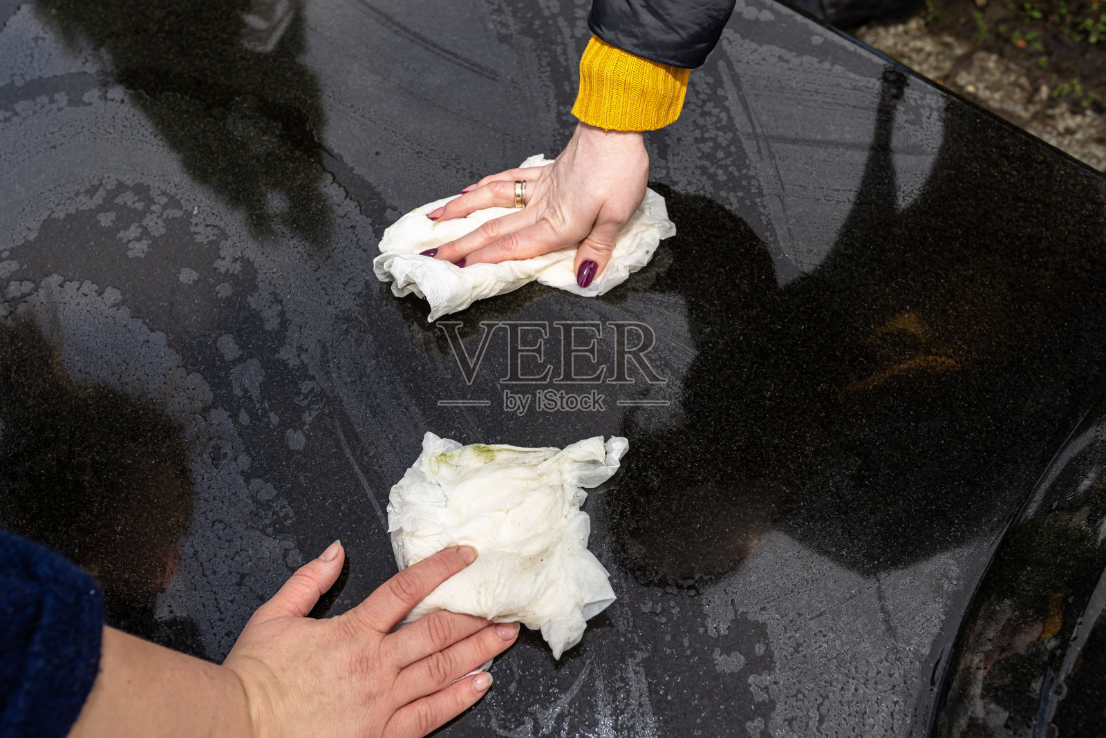 用布和水清洁黑色墓碑，可见女性的手照片摄影图片