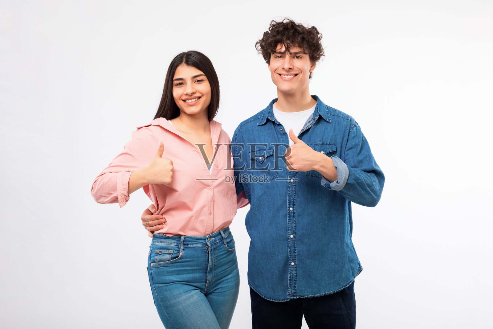 快乐的年轻夫妇在随意的手势竖起大拇指，白色背景照片摄影图片