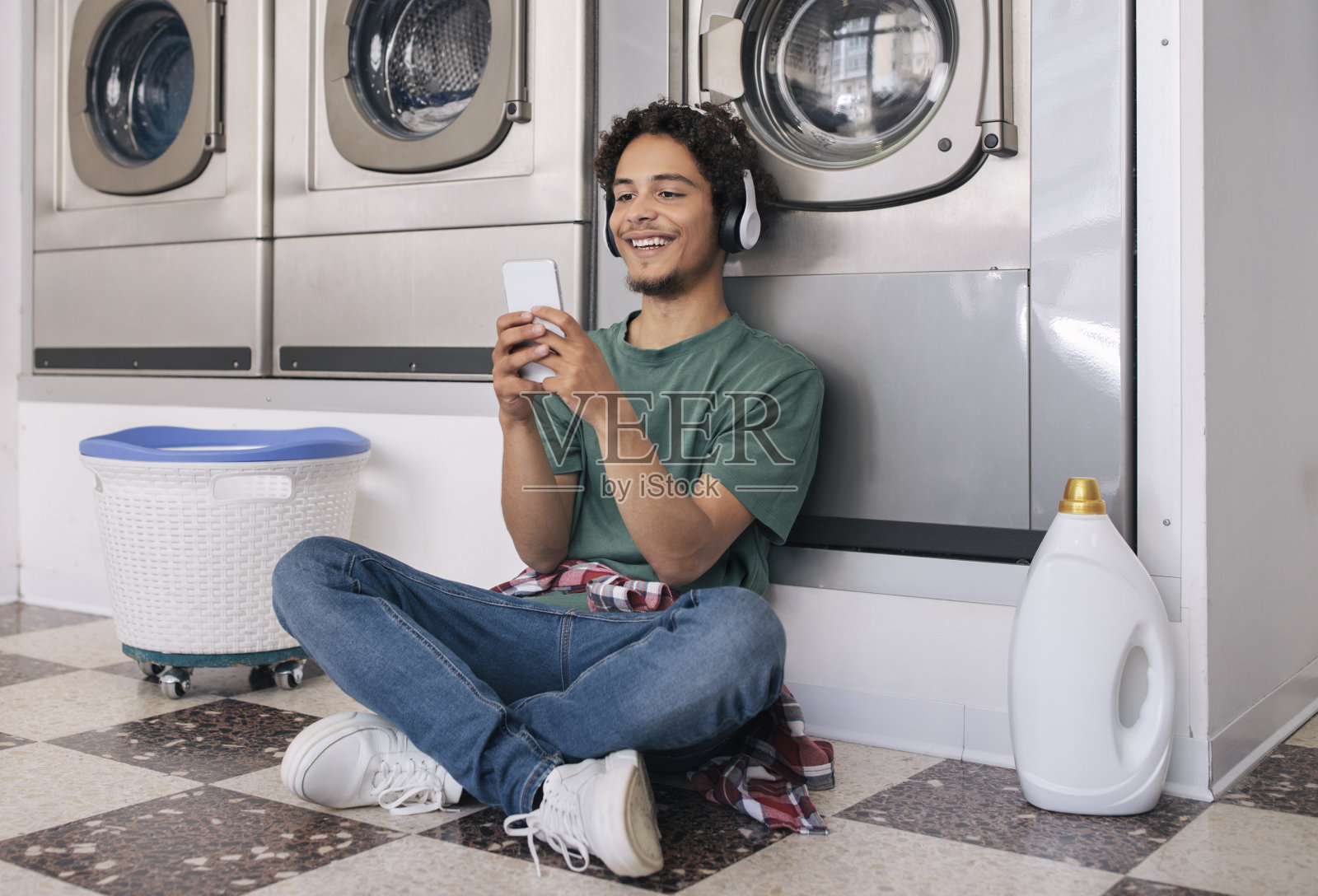 一个人在洗衣机里用智能手机洗衣服照片摄影图片