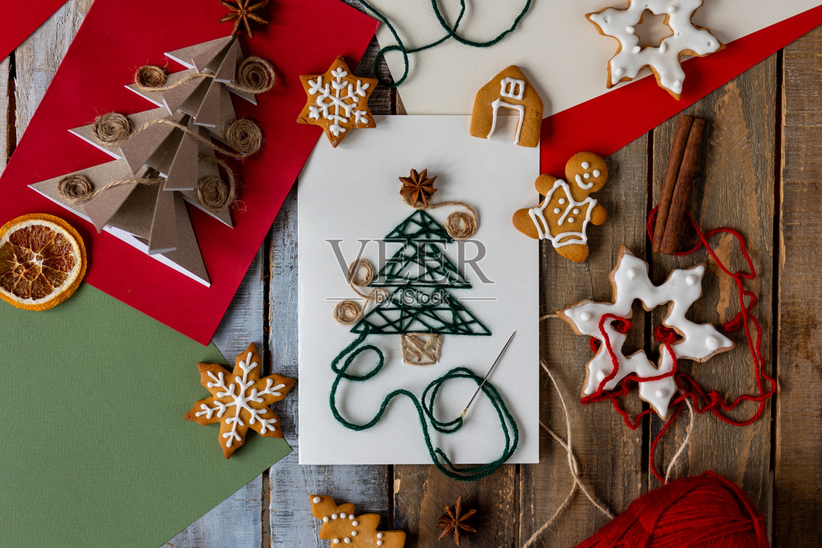 新年平躺顶视图与手工纸卡与羊毛线刺绣，圣诞姜饼饼干，木制背景的节日装饰。温馨的家庭氛围，家庭时光照片摄影图片