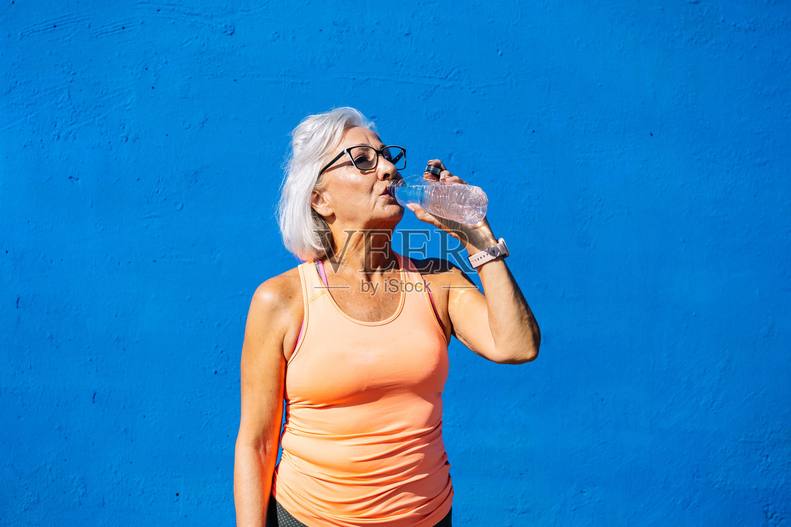 口渴的老妇人边运动边喝水照片摄影图片