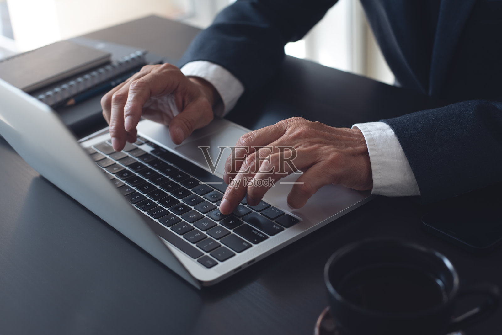 商人在线工作在笔记本电脑上，上网冲浪，网络在现代办公室，特写。商务人士在办公桌上用手提电脑键盘打字照片摄影图片