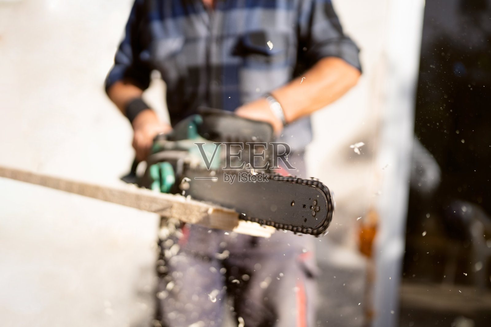 无法辨认的建筑工人在用电锯锯木头照片摄影图片