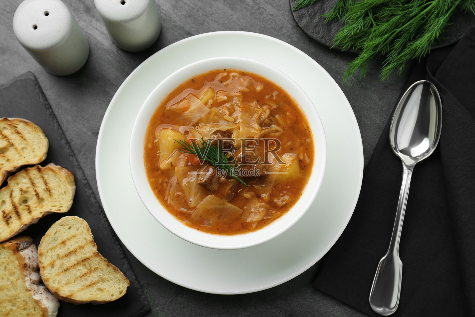 美味的卷心菜汤，肉，胡萝卜和莳萝在黑色的桌子上，平铺照片摄影图片