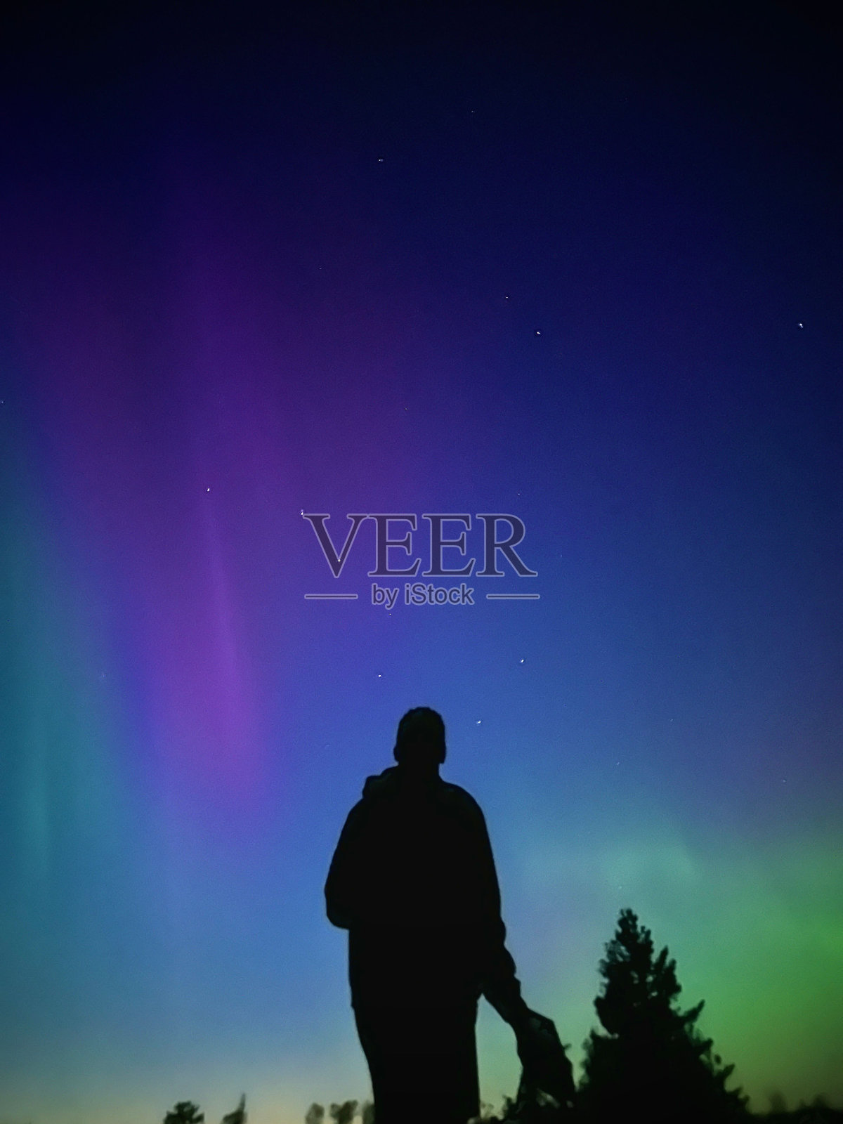 一个敬畏的男人的剪影，在夜空中美丽而充满活力的极光的背景下照片摄影图片