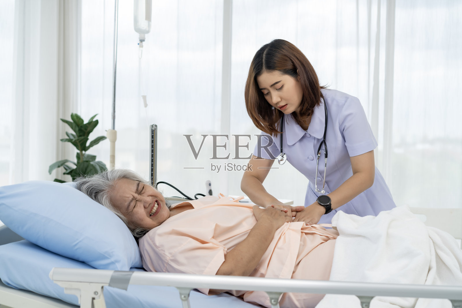 一位老年病人的护士或护工正在帮助患有严重胃病的病人照片摄影图片