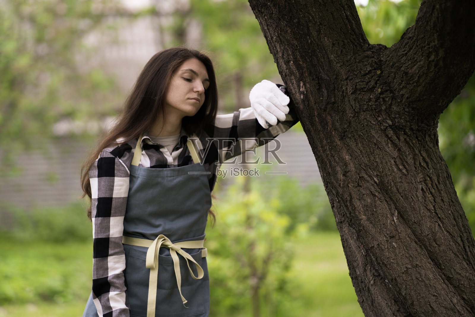 在花园里干完活后，一个穿着围裙、疲惫不堪的年轻姑娘照片摄影图片