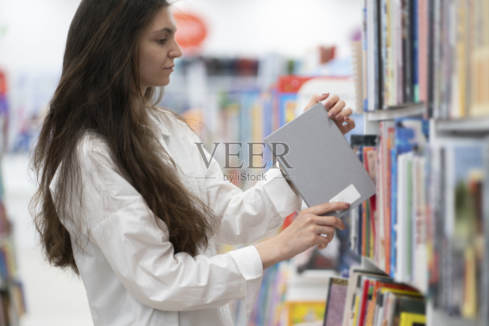 一个女人在书店里拿着一本书读着照片摄影图片