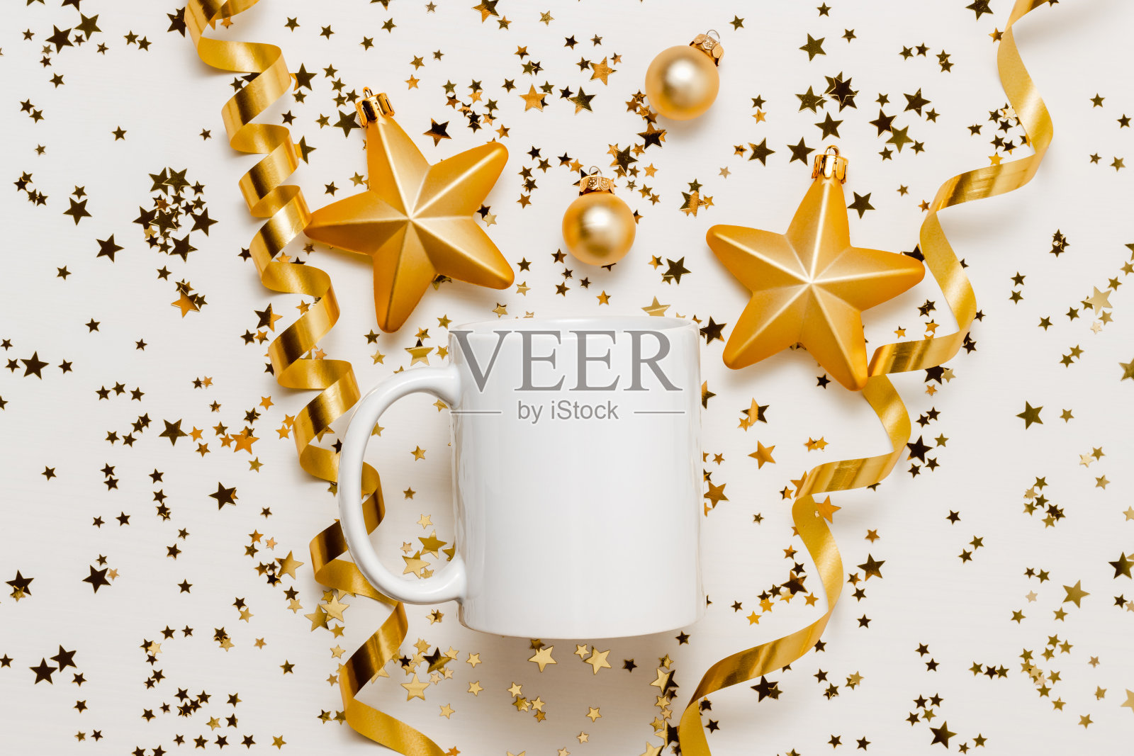 白色模拟马克杯与闪闪发光的彩纸星星和金色丝带在白色木制背景照片摄影图片