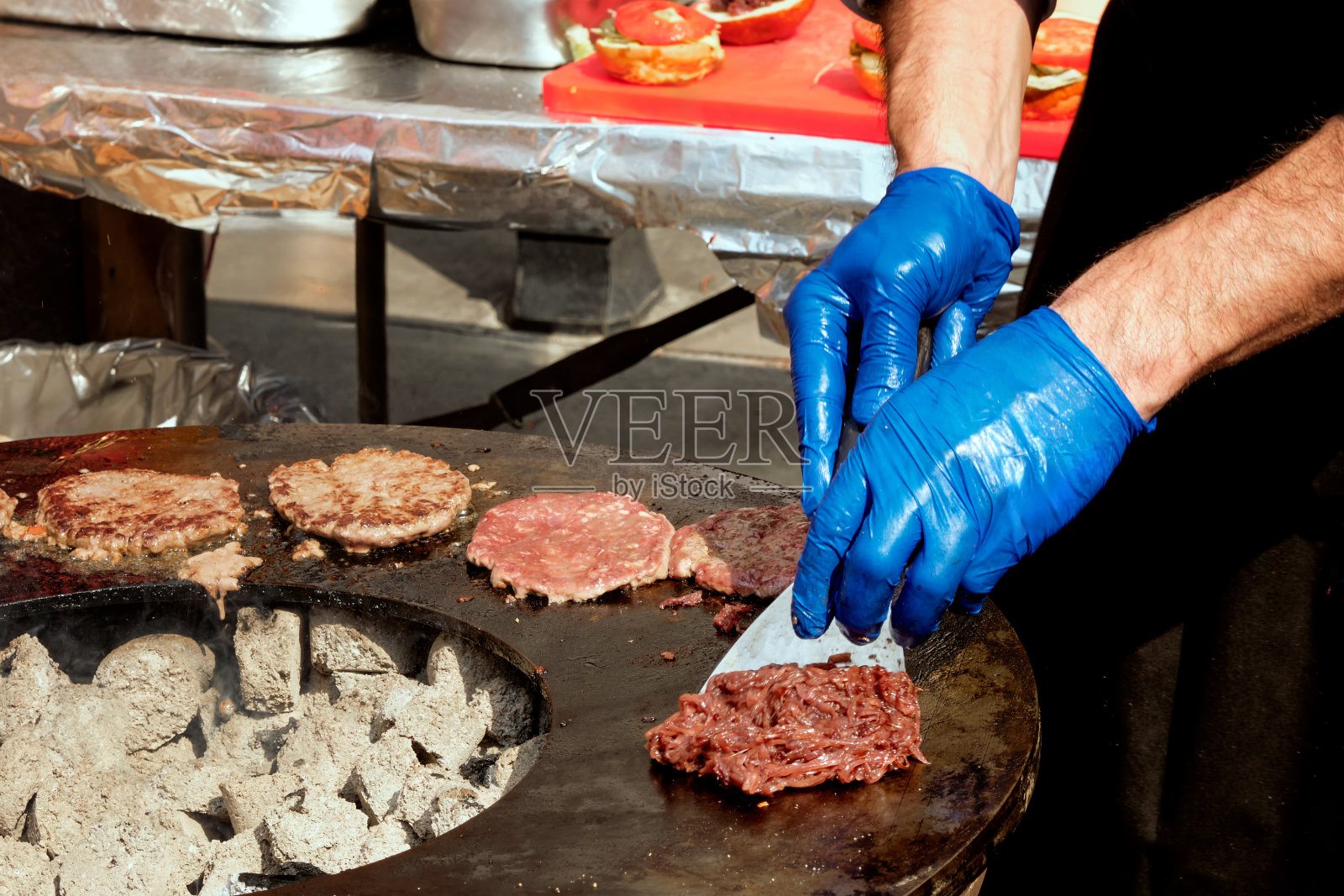 男厨师在露天烤架上煎肉饼。照片摄影图片
