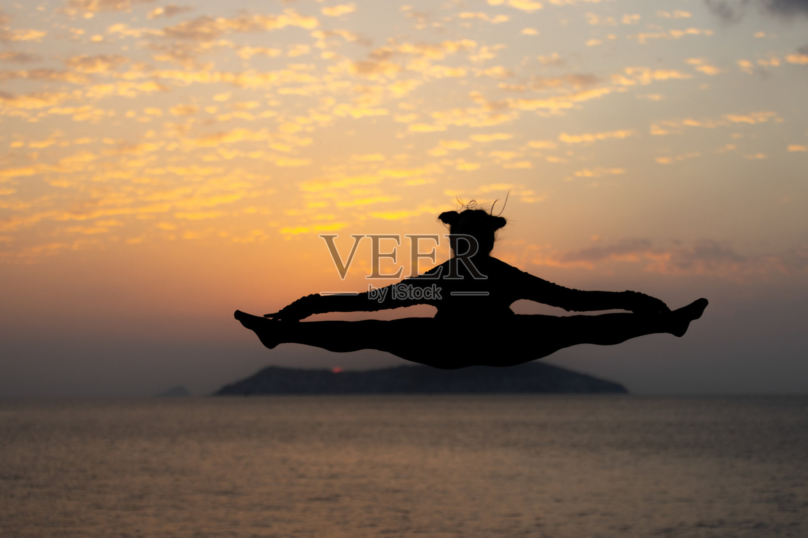 柔韧的年轻女子在日落时跳跃。照片摄影图片