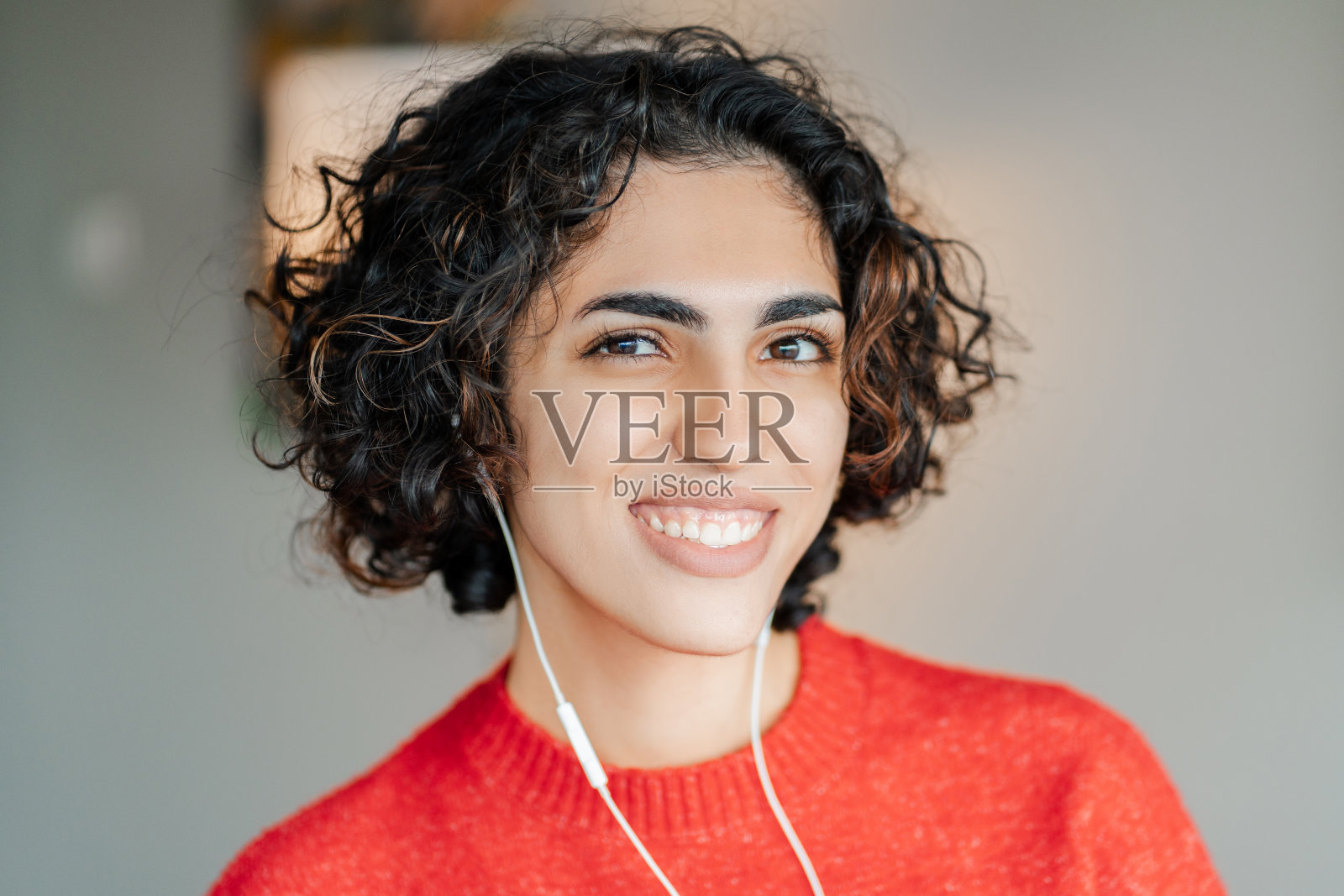 面带微笑的中东女性戴着耳机听音乐，看着镜头照片摄影图片