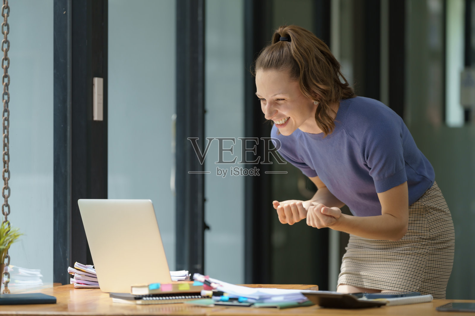 办公室里一位成功的女商人对自己的成就感到满意，而员工则完成了一项技术任务，并举起双手，做出了胜利的手势。照片摄影图片