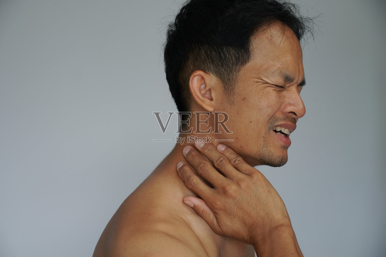 亚洲男人因在家工作而脖子疼。办公室综合症。照片摄影图片