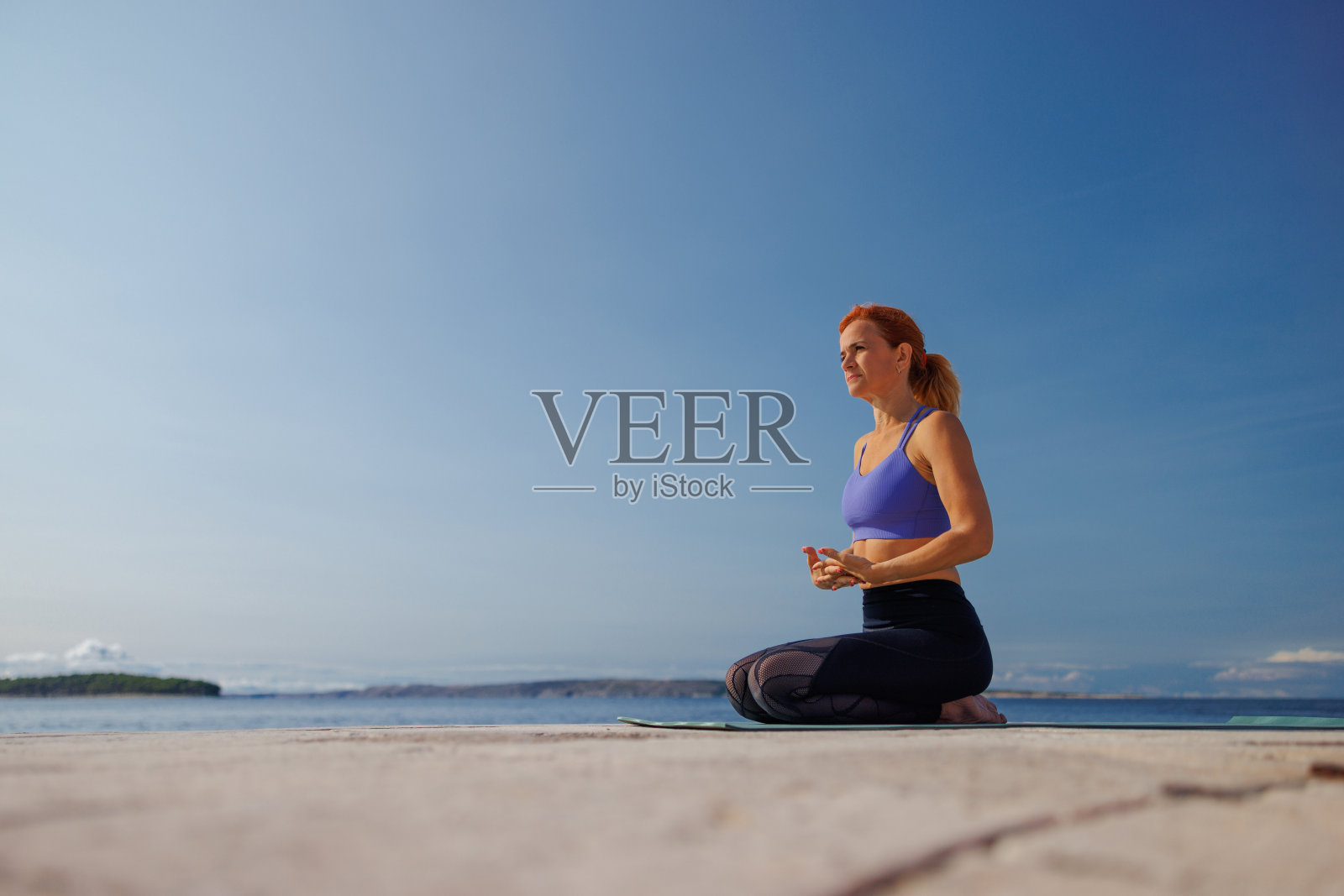 健康的中年妇女，穿着运动服，坐在运动垫上暖手照片摄影图片