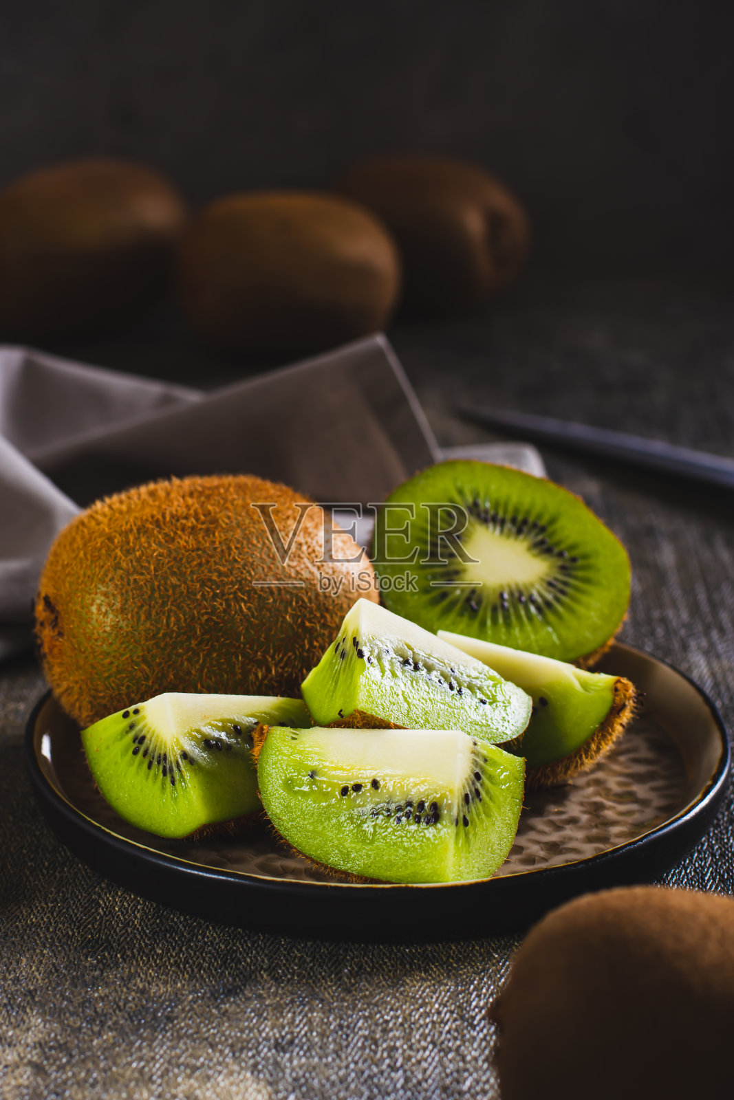 新鲜成熟的猕猴桃切片放在桌子上的盘子上垂直观看照片摄影图片