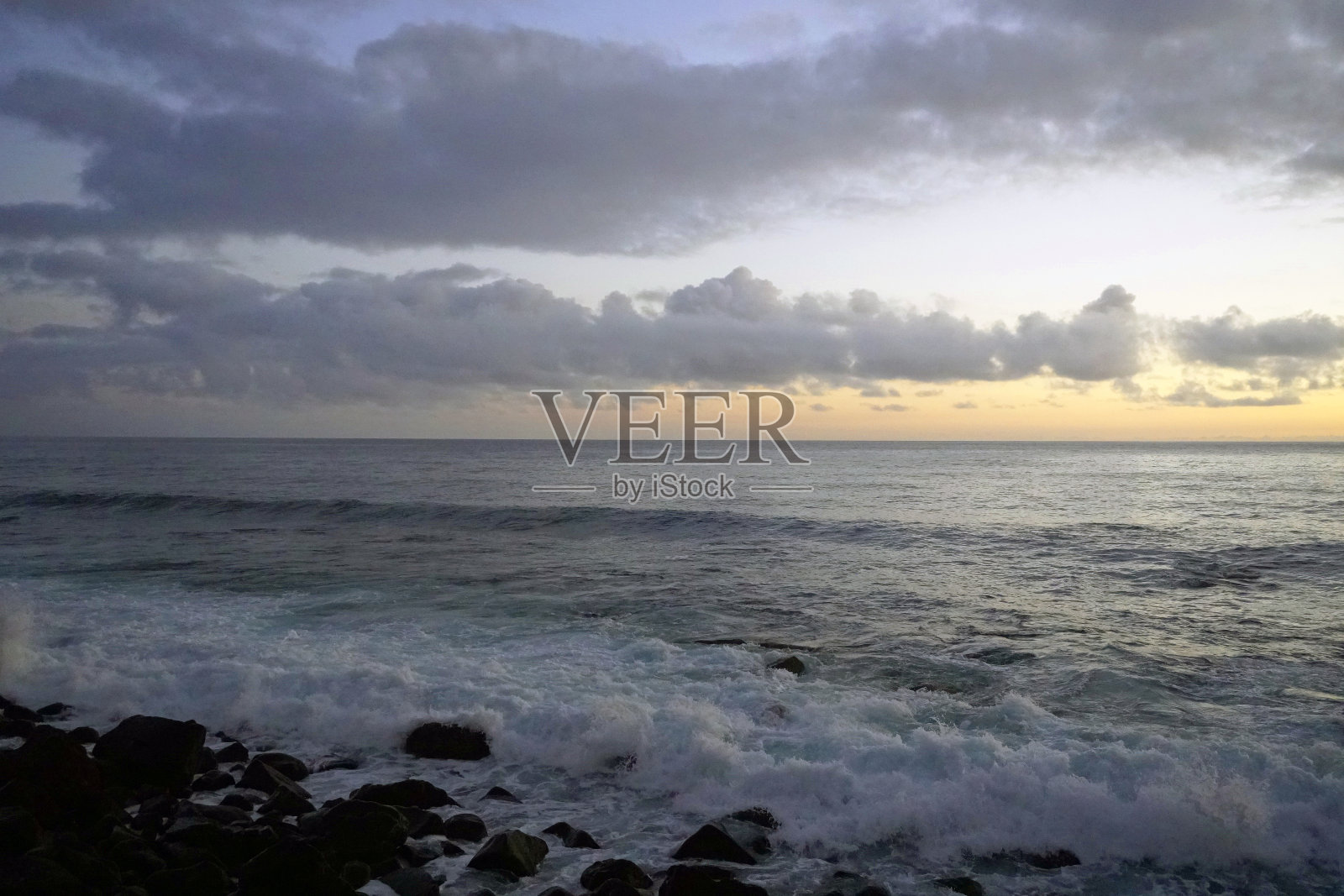 马德拉岛早晨的海面。海岸的岩石。和粉色的云在朝阳的光芒中。海浪上的眩光和反射。水平射照片摄影图片