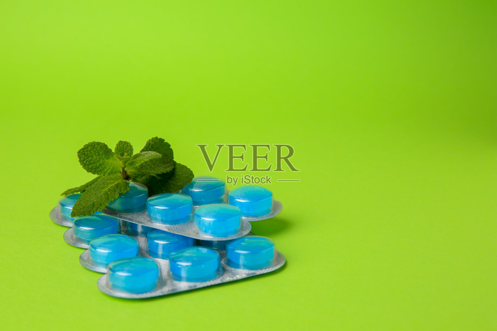 水泡与咳嗽药水和薄荷叶在浅绿色的背景。文本空间照片摄影图片