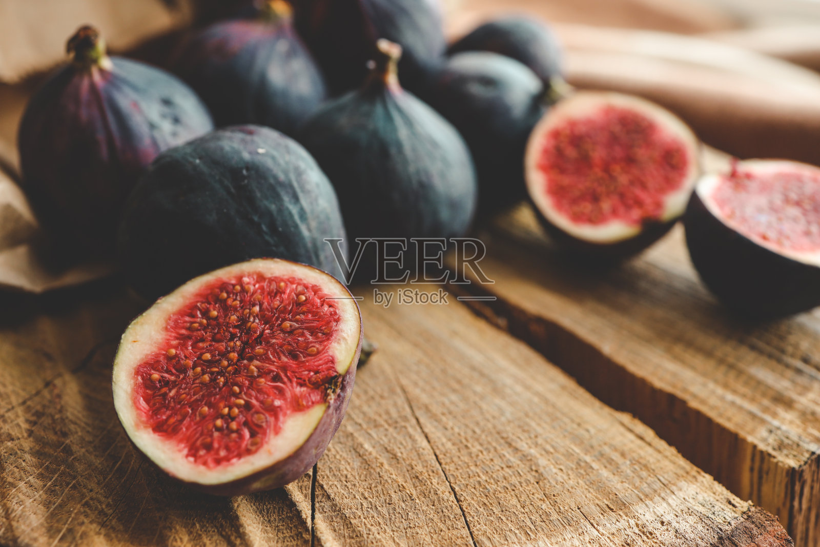 在一个古老的木制背景上，碗里放着几颗无花果。照片摄影图片