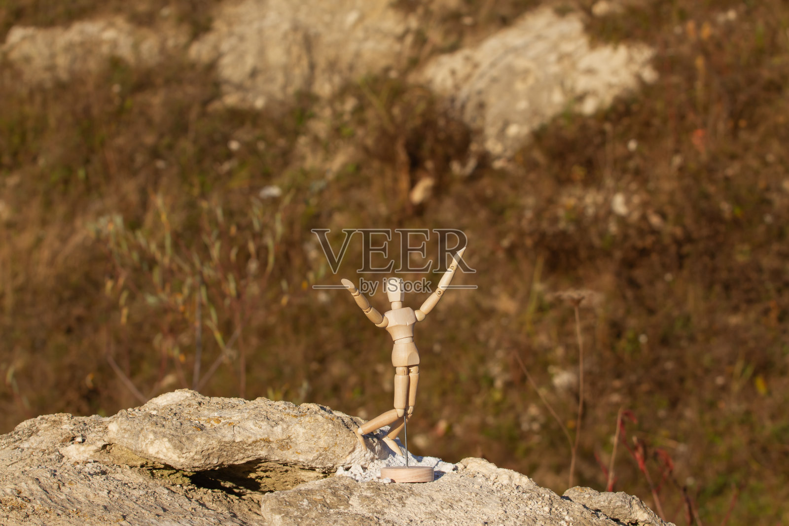 一座木雕雕像在山顶上举起了双手。胜利的概念。照片摄影图片