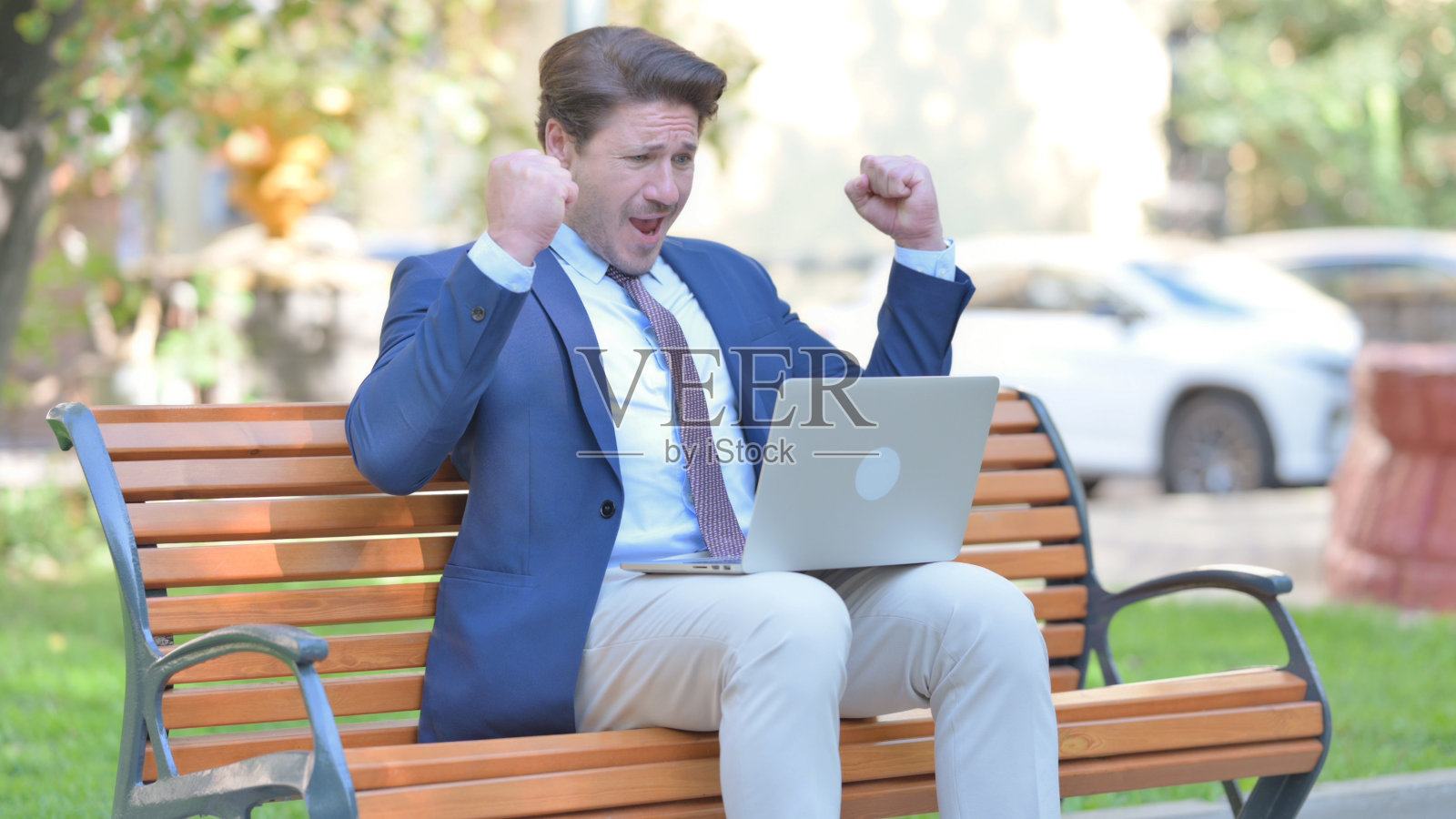 自信的商人在笔记本电脑户外庆祝成功照片摄影图片