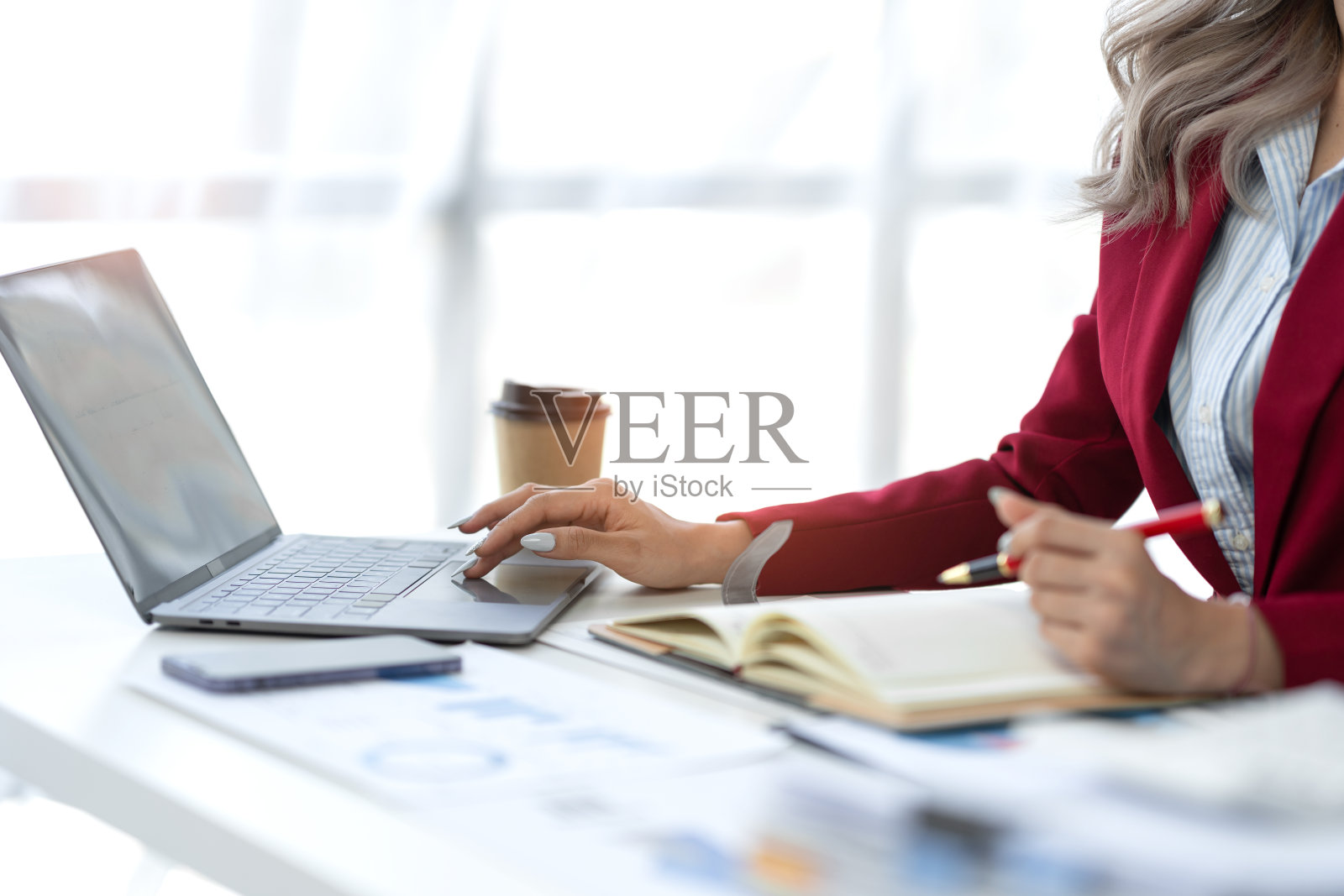 商务女性坐在笔记本上做笔记，在笔记本上记录公司财务收入和预算，计算每月费用，管理预算，贷款，发票。金融的概念。照片摄影图片