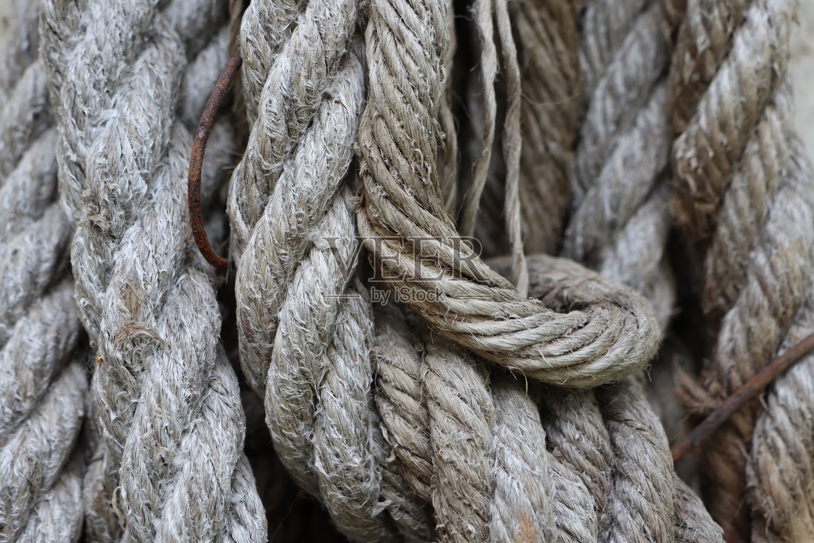 老土司绳挂在墙上的一根钉子上，有户外纹理的背景照片摄影图片