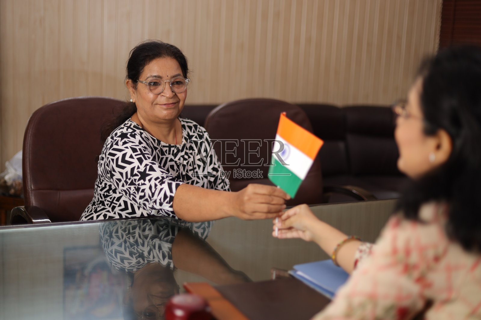 高高在上的镜头，快乐自豪的校长给一位老老师颁发印度国旗作为奖励，因为她在学校服务了很长时间。照片摄影图片