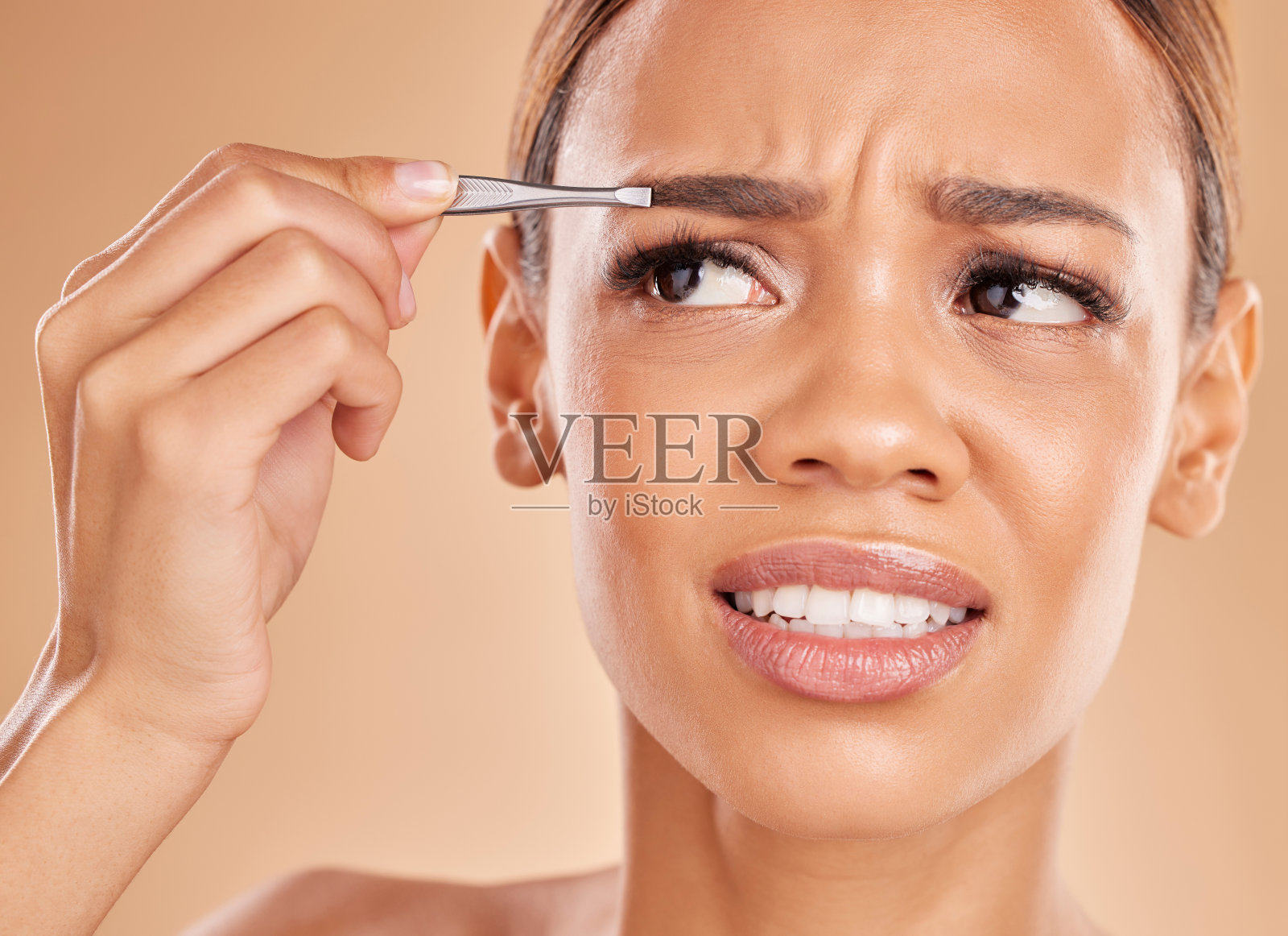 疼痛，脱毛和眉毛用女人和镊子在工作室清洁，自我护理和化妆品。面部，拔毛和形状的女性模特在棕色背景为美容和护肤照片摄影图片