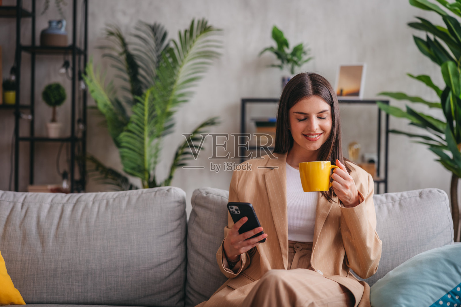 漂亮的年轻女子在家里用她的智能手机照片摄影图片