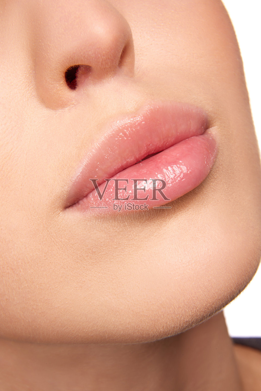 近距离观察女性饱满的粉红色与自然光泽的嘴唇，闭上嘴巴。美丽丰满的嘴唇。治疗后，滋润嘴唇。照片摄影图片
