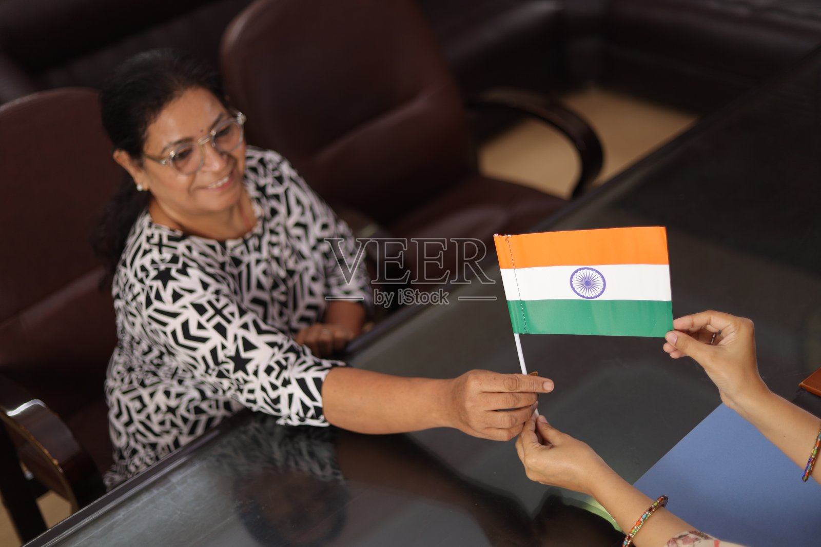 高高在上的镜头，快乐自豪的校长给一位老老师颁发印度国旗作为奖励，因为她在学校服务了很长时间。照片摄影图片