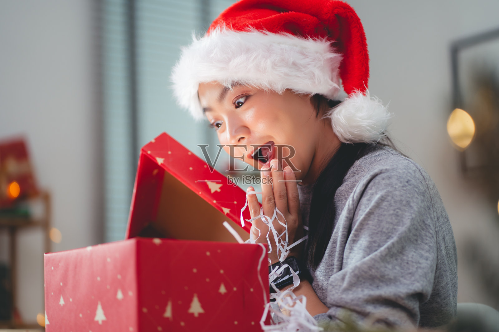 亚洲女人在圣诞节打开礼品盒时玩得很开心。照片摄影图片