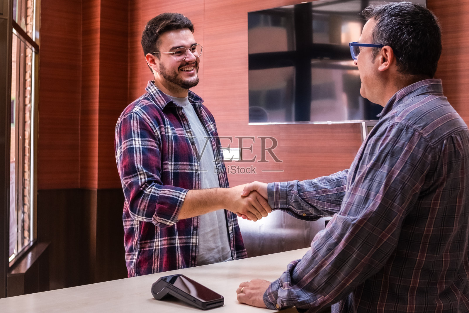 一位顾客和当地一家小企业的老板握手并互相问候。照片摄影图片