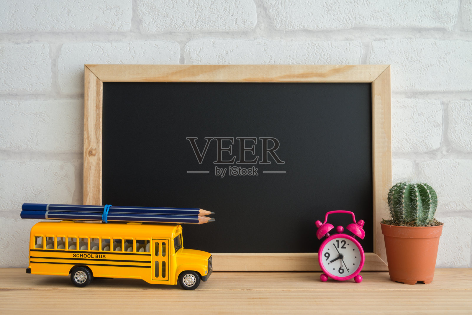 空白的黑板，校车，闹钟和仙人掌花盆与白色的墙壁背景。照片摄影图片
