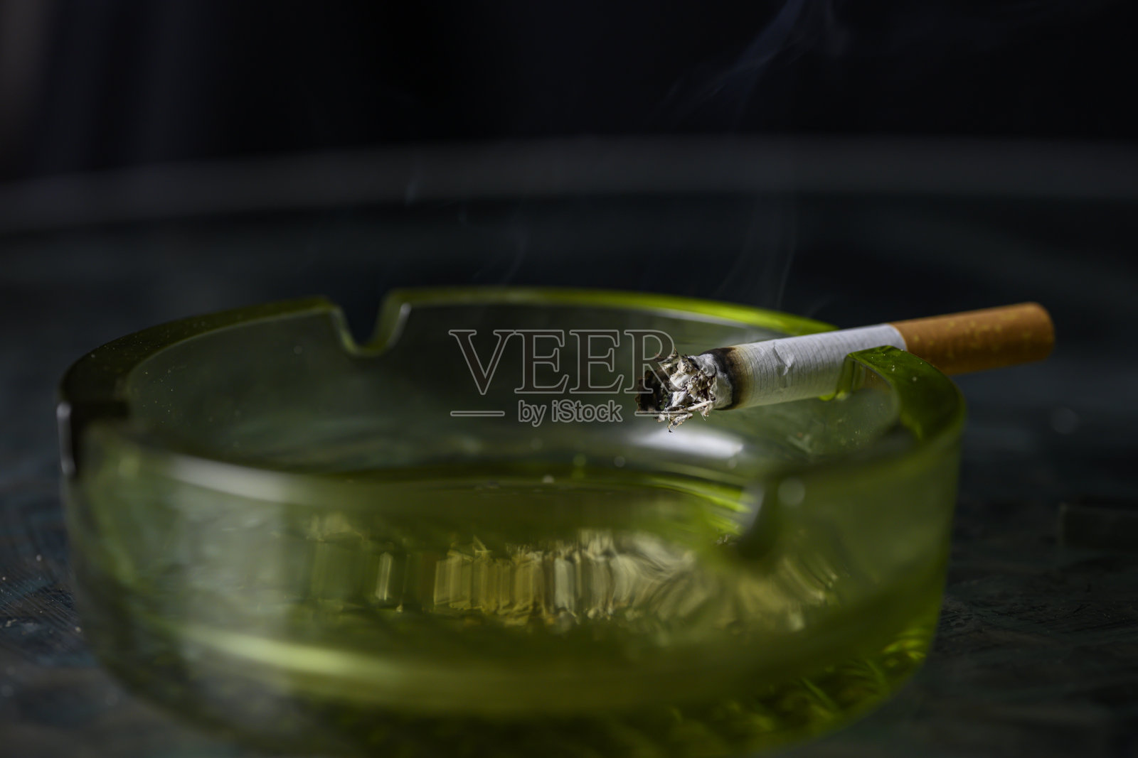 点燃的香烟在烟灰缸里燃烧照片摄影图片