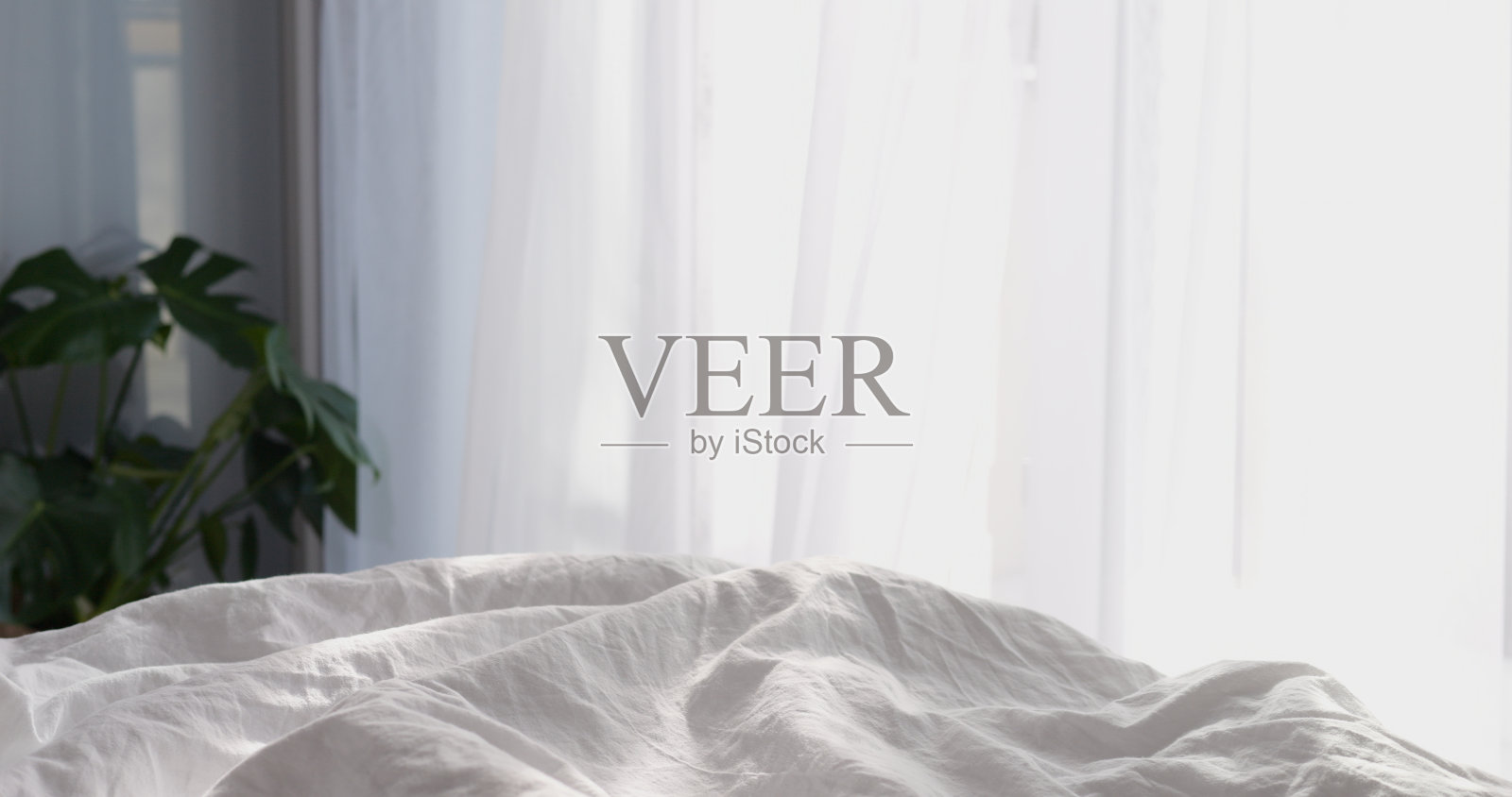 在阳光明媚的日子里，卧室窗户边的床上铺着白色的棉毯。愉快和舒适的春天或夏天的早晨气氛在新的一天的早期开始照片摄影图片